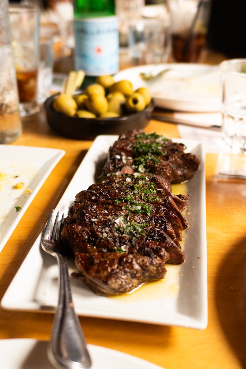 A platter of sliced steak and olives on a lunch table